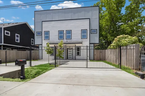 a view of a brick house with a small yard and a large tree
