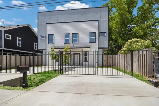 a view of a brick house with a small yard and a large tree