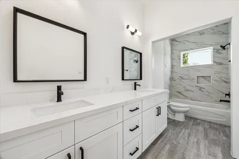 a bathroom with a double vanity sink toilet and mirror