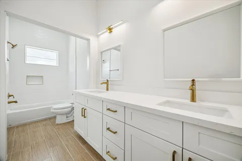 a spacious bathroom with a double vanity sink a toilet and a bathtub