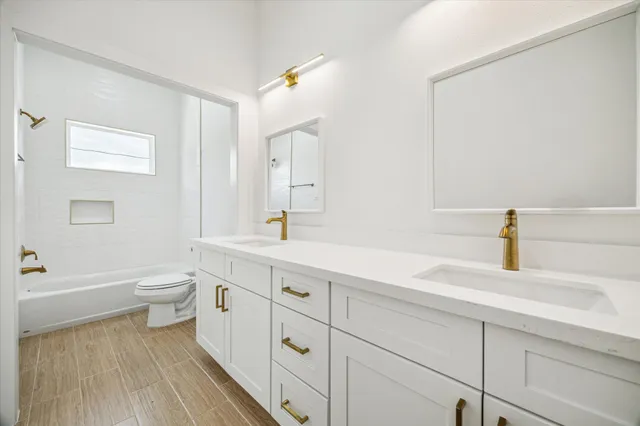 a spacious bathroom with a double vanity sink a toilet and a bathtub