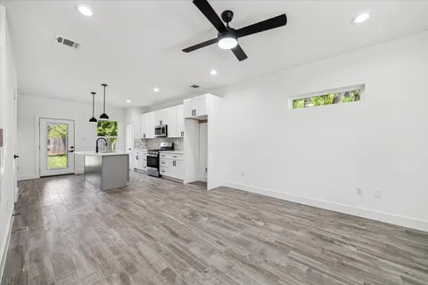 a view of a kitchen with a refrigerator a ceiling fan and wooden floor