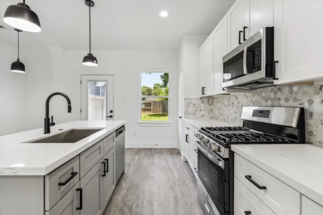 a kitchen with stainless steel appliances a sink stove and microwave