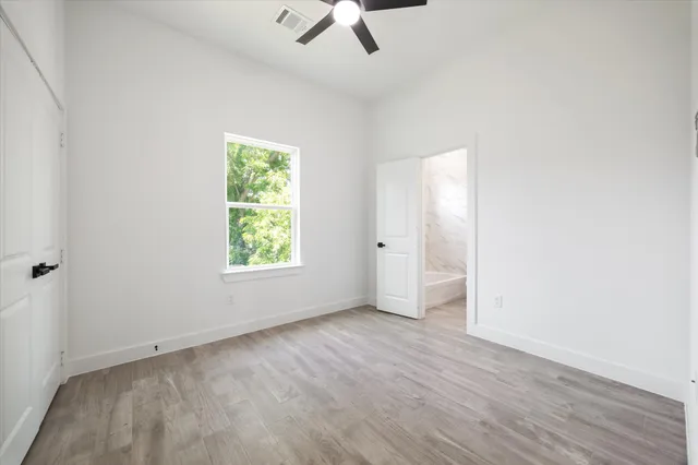 an empty room with a window and a ceiling fan