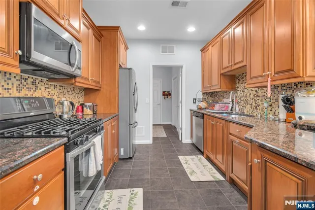 a kitchen with stainless steel appliances granite countertop a stove a sink dishwasher and a refrigerator