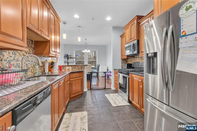 a kitchen with stainless steel appliances granite countertop a refrigerator and a stove top oven