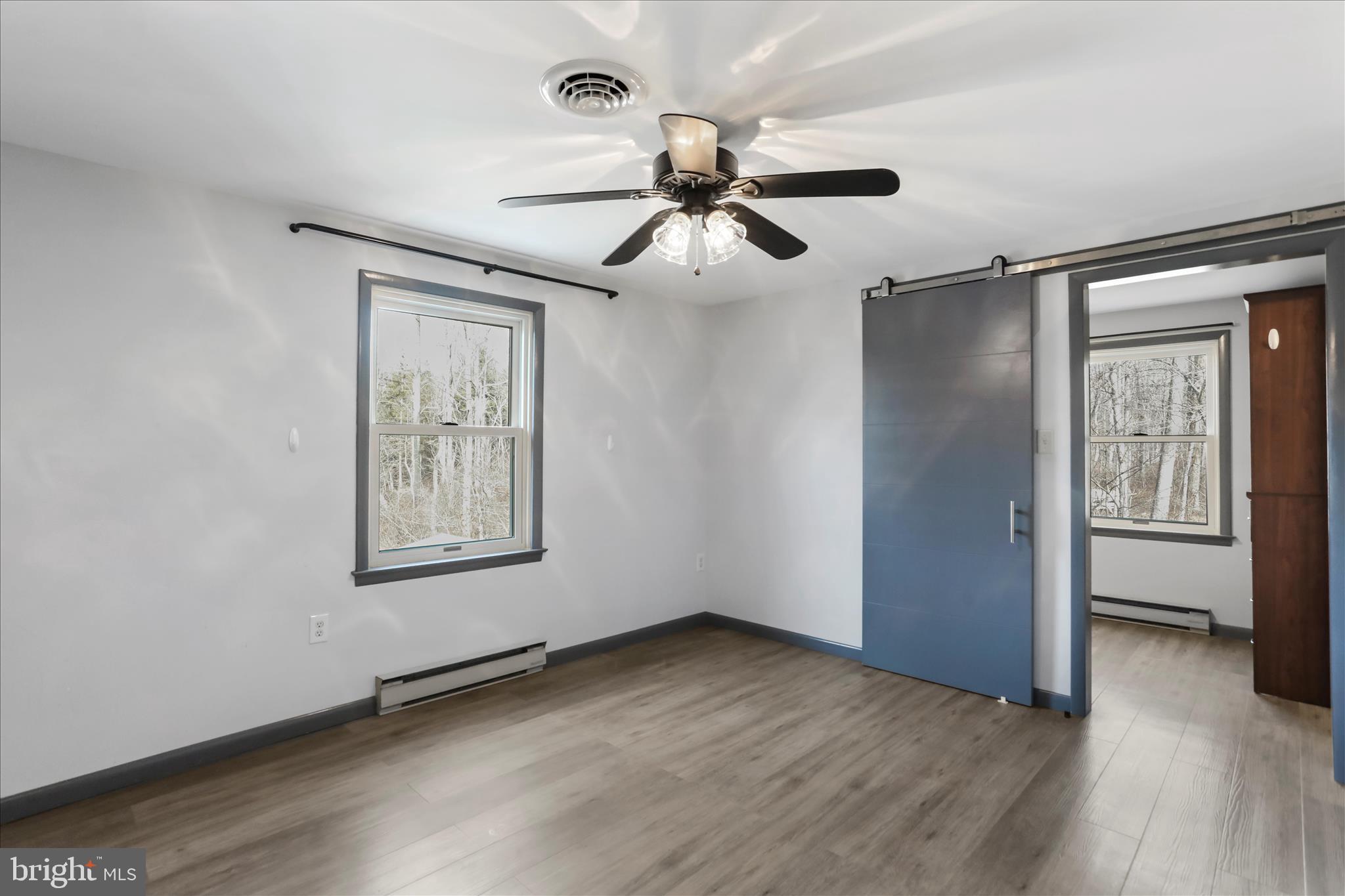 24744 Raven Rock Road Smithsburg, MD 21783 - Photo 18 of 49 an empty room with wooden floor chandelier fan and windows