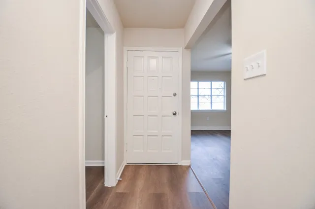 an empty room with wooden floor closet and windows