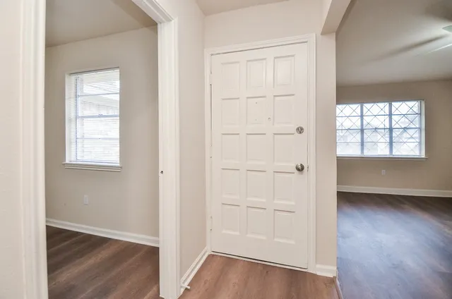 an empty room with wooden floor closet and windows