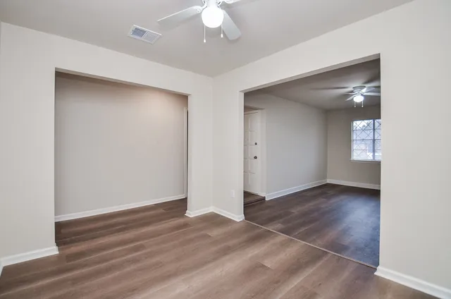 an empty room with wooden floor and windows