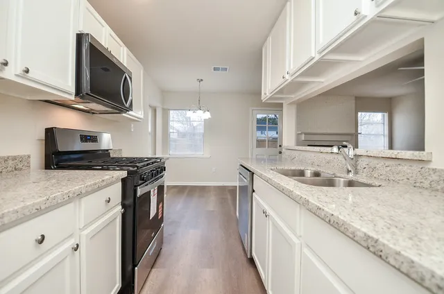 a kitchen with stainless steel appliances granite countertop a sink stove microwave and cabinets