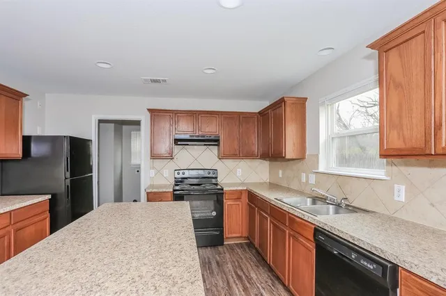 a kitchen with stainless steel appliances granite countertop a sink stove refrigerator and window