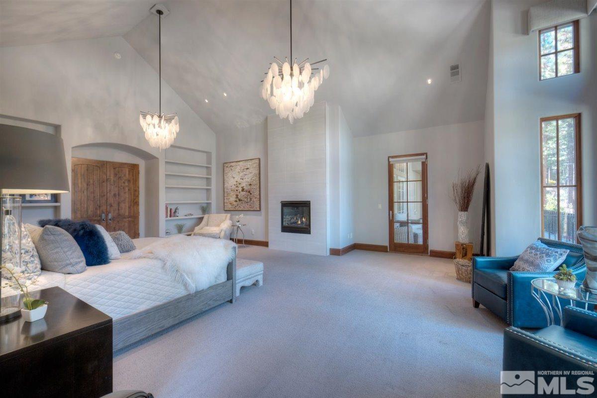 6090 Lake Geneva Drive Reno, NV 89511 - Photo 15 of 40 a spacious bedroom with a bed a bookshelf and a chandelier