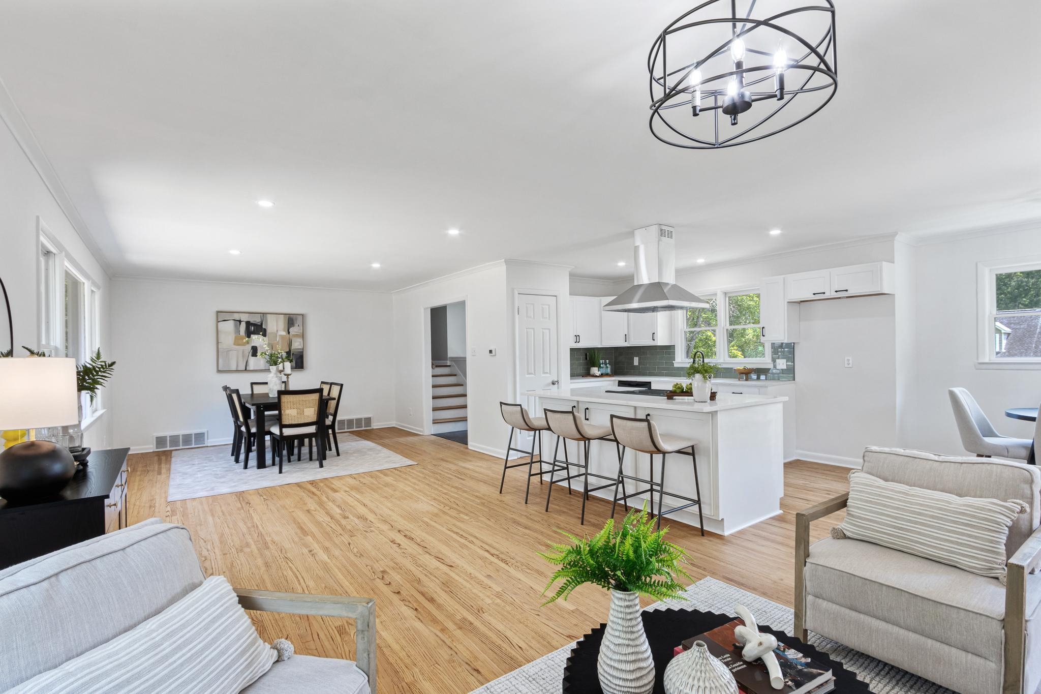 5504 Normandy Road Memphis, TN 38120 - Photo 3 of 34 Open-concept living, dining, and kitchen layout with refinished hardwood floors, modern lighting, and large windows offering abundant natural light. Spacious island seating and seamless flow create a perfect setting for entertaining and everyday comfort