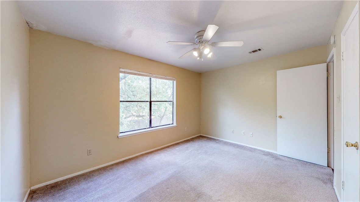 301 Manuel Drive, Unit C College Station, TX 77840 - Photo 12 of 25 an empty room with chandelier fan and windows