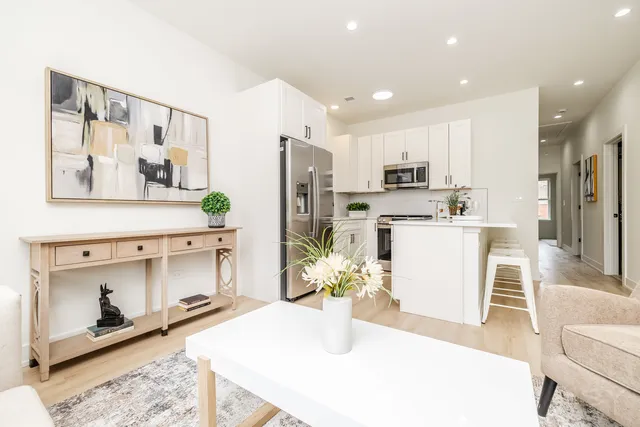 a kitchen with stainless steel appliances kitchen island granite countertop a refrigerator a stove a sink and white cabinets with wooden floor