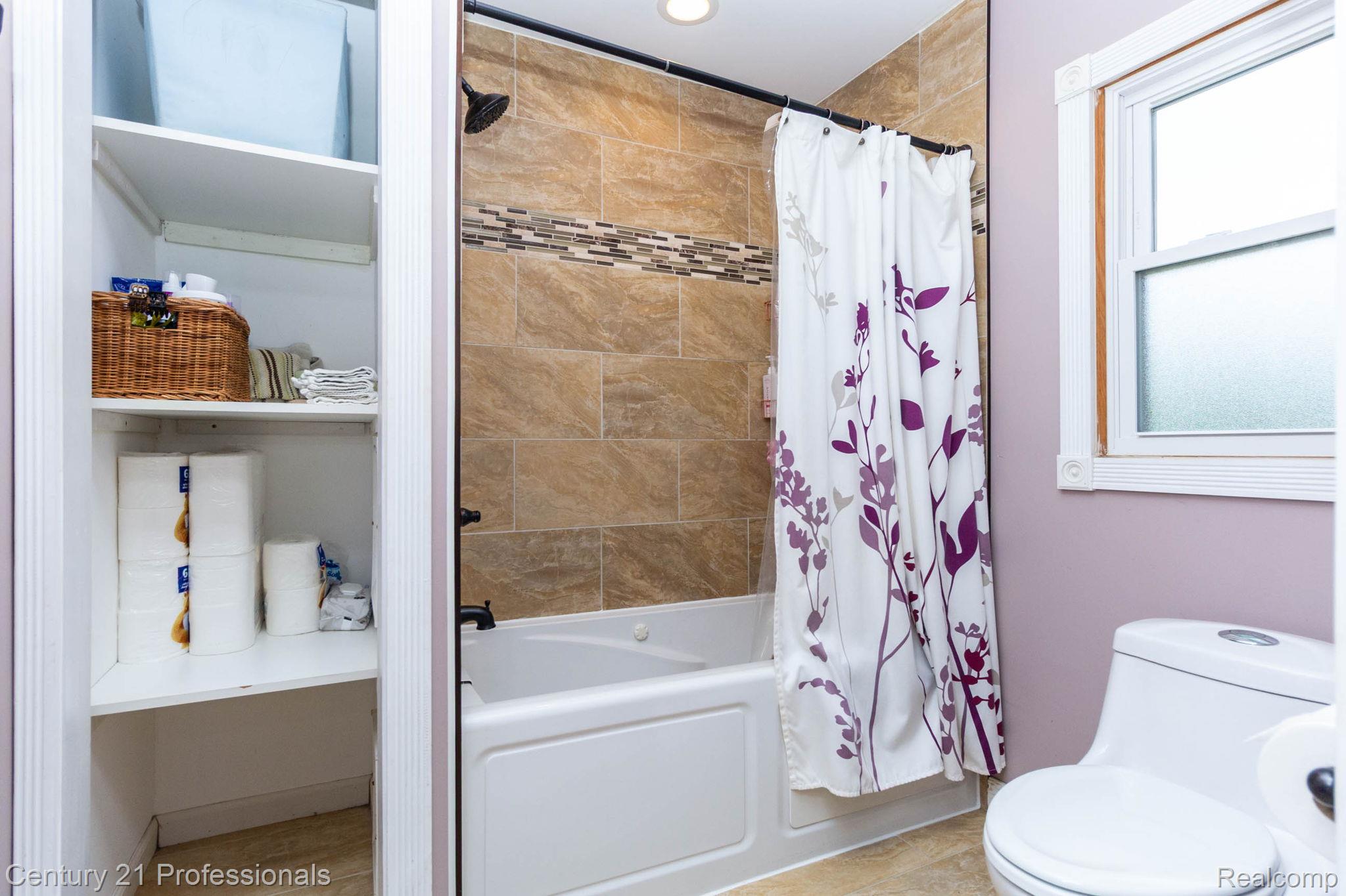 671 Bridgestone Drive Rochester, MI 48309 - Photo 25 of 50 Bathroom featuring a jetted tub/shower combination with tile surround, built-in shelving, a single window, and a white toilet