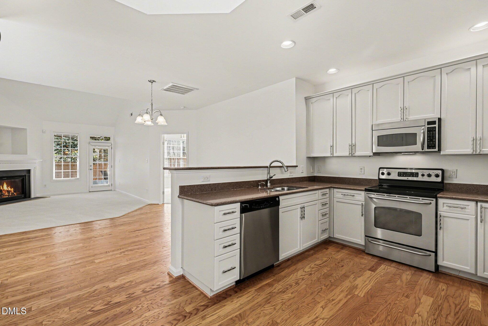 723 Swan Neck Lane Raleigh, NC 27615 - Photo 50 of 52 a kitchen with stainless steel appliances granite countertop a stove a sink and white cabinets