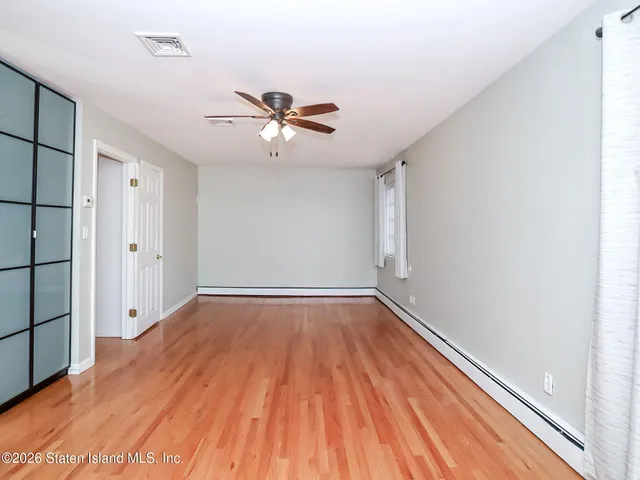 a view of empty room with wooden floor and fan