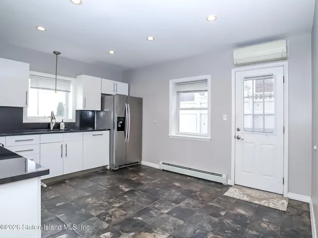 a large white kitchen with a refrigerator a stove a sink and a window