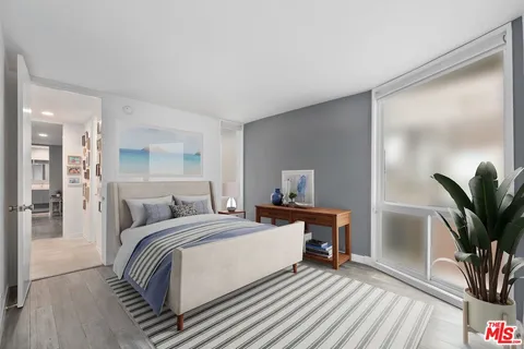 a bedroom with a bed and a potted plant on the dresser