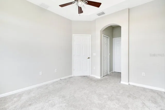 an empty room with ceiling fan and window