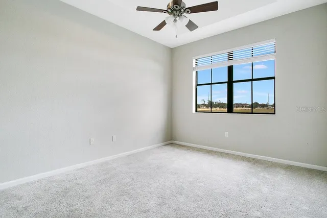 an empty room with windows and fan