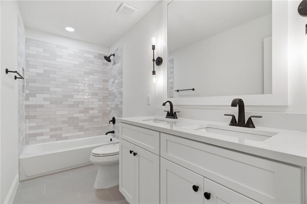 3447 Dry Creek Road Marietta, GA 30062 - Photo 22 of 42 a bathroom with a granite countertop toilet a sink a mirror and bathtub