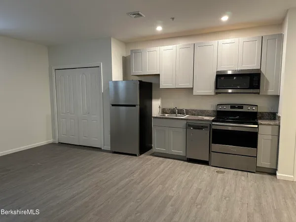 a kitchen with granite countertop a refrigerator and a stove top oven
