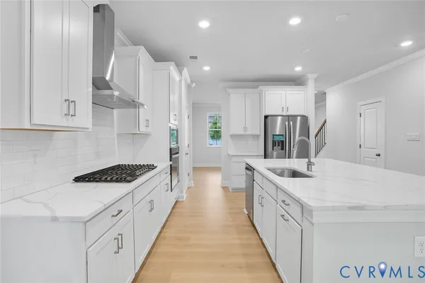 a large white kitchen with stainless steel appliances lots of counter space and wooden floor