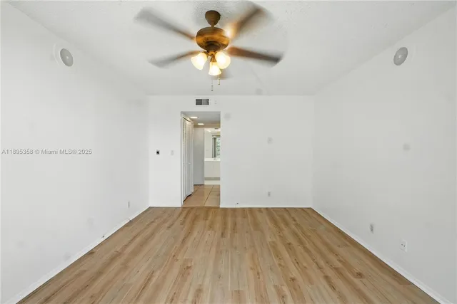 a view of a room with wooden floor and a ceiling fan