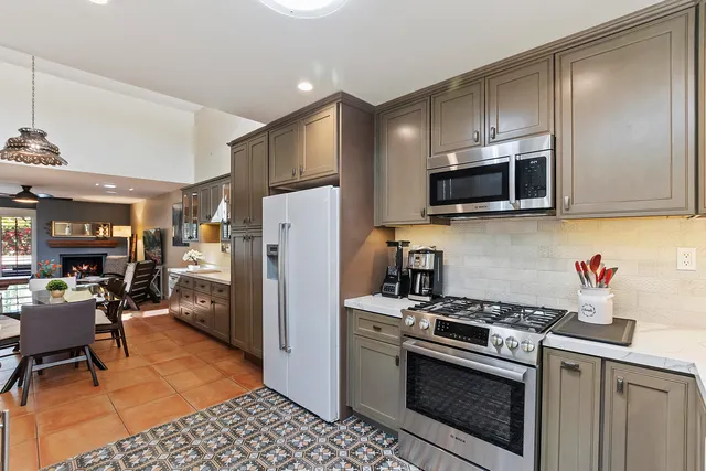 a kitchen with stainless steel appliances a refrigerator a stove a sink cabinets and a dining table