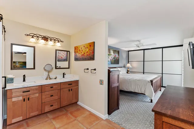 a en suite bathroom with double vanity a mirror and a lamp