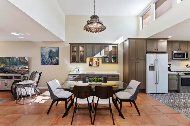 a dining room with stainless steel appliances a table and chairs