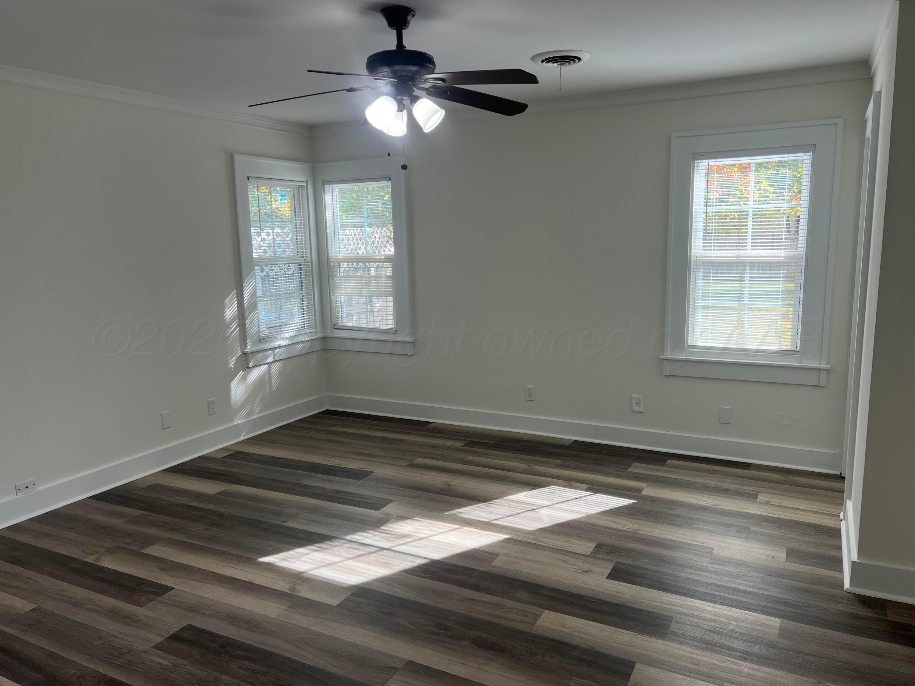 4233 Southwest 13th Avenue Amarillo, TX 79106 - Photo 11 of 55 an empty room with wooden floor chandelier fan and windows