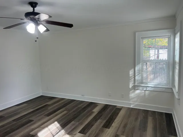 en empty room with wooden floor fan and window