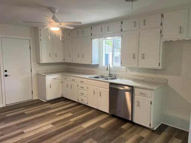 a kitchen with granite countertop white cabinets stainless steel appliances and a sink