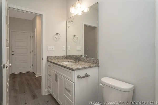a bathroom with a granite countertop toilet a sink a mirror and a window