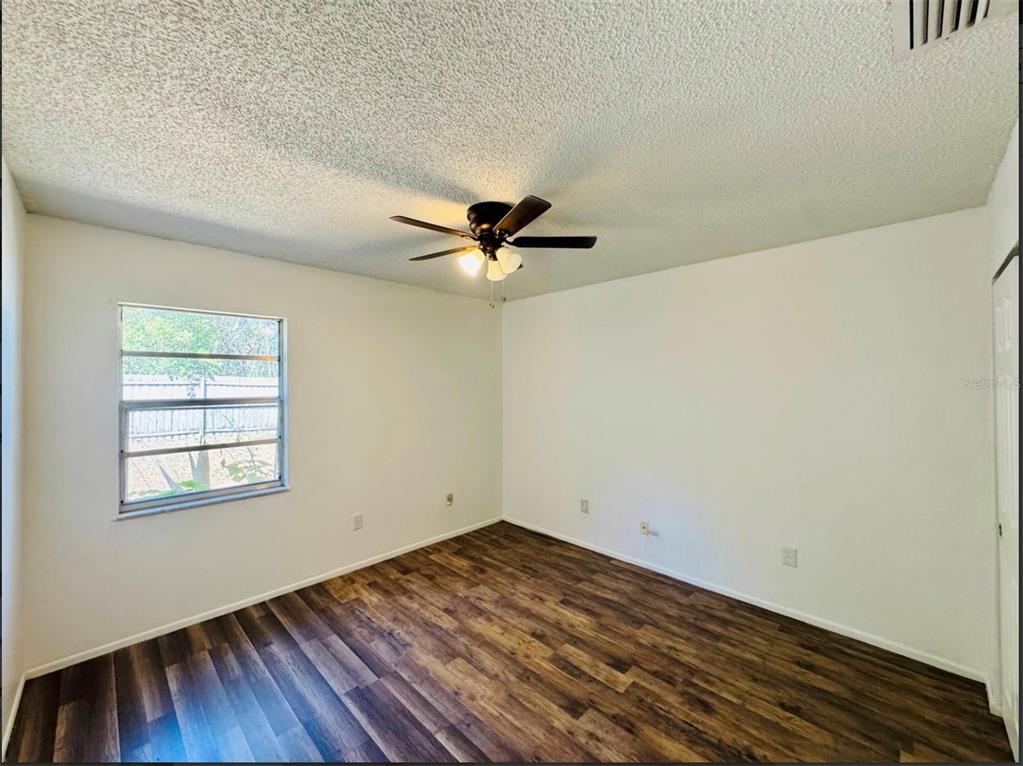 7423 Mohawk Trail Spring Hill, FL 34606 - Photo 11 of 20 an empty room with wooden floor ceiling fan and windows
