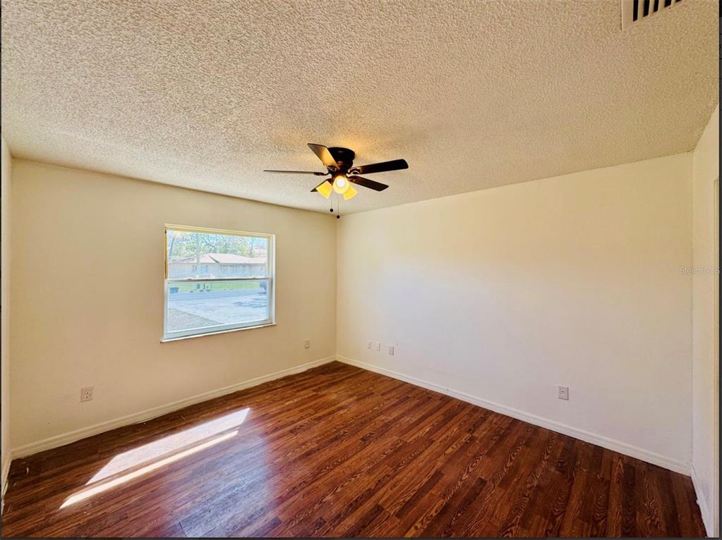 7423 Mohawk Trail Spring Hill, FL 34606 - Photo 13 of 20 a view of a room with wooden floor and a ceiling fan