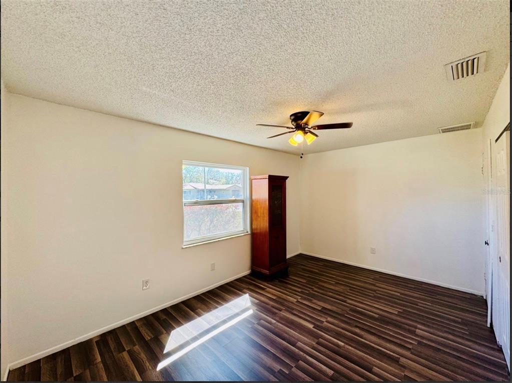 7423 Mohawk Trail Spring Hill, FL 34606 - Photo 15 of 20 a view of an empty room with wooden floor and a window