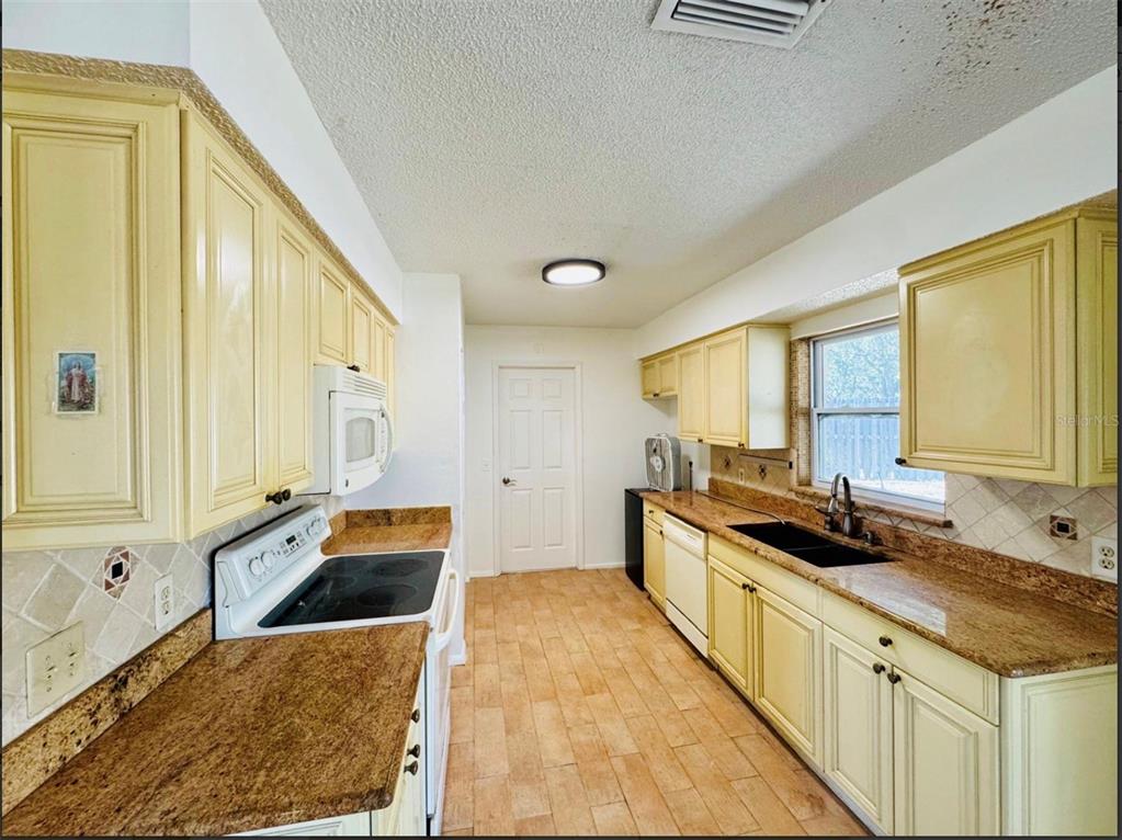 7423 Mohawk Trail Spring Hill, FL 34606 - Photo 17 of 20 a kitchen with a stove a sink and a refrigerator