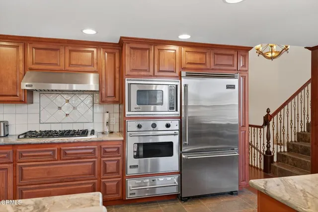 a kitchen with stainless steel appliances granite countertop a refrigerator and a stove