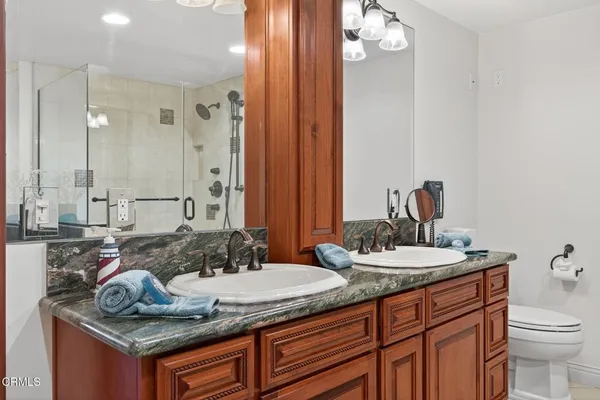 a bathroom with a granite countertop double vanity sink and mirror