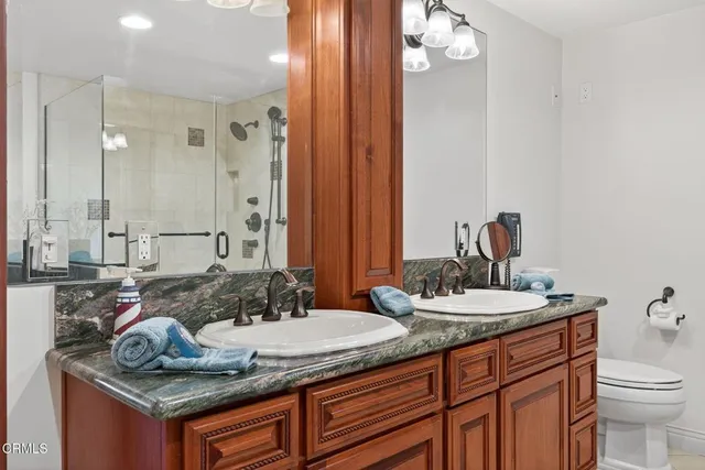 a bathroom with a granite countertop double vanity sink and mirror