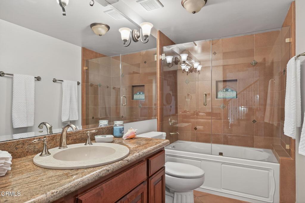 2408 Ocean Drive Oxnard, CA 93035 - Photo 42 of 58 a bathroom with a granite countertop sink a toilet a mirror and shower