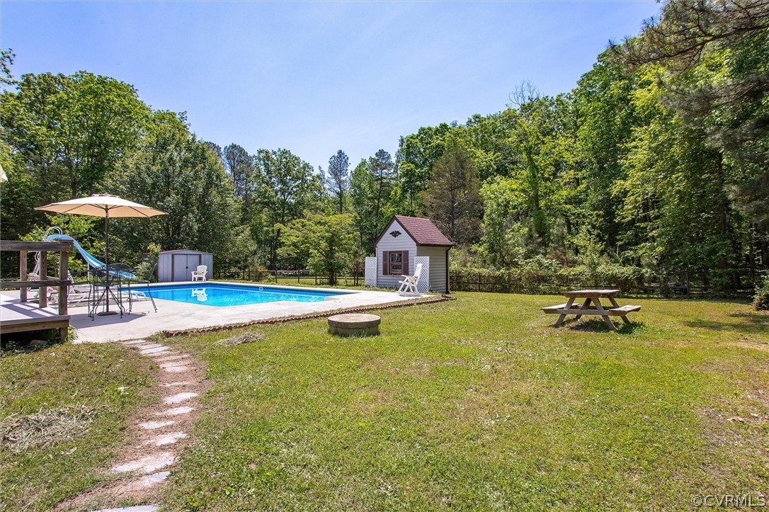 22601 Skinquarter Road Moseley, VA 23120 - Photo 34 of 50 a view of a swimming pool with lawn chairs under an umbrella