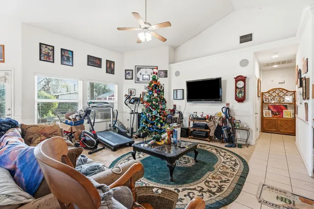 a view of an empty room with window and chandelier fan