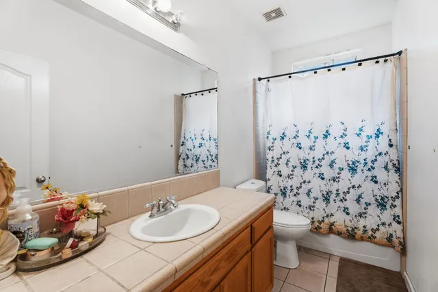an empty room with wooden floor chandelier fan and windows