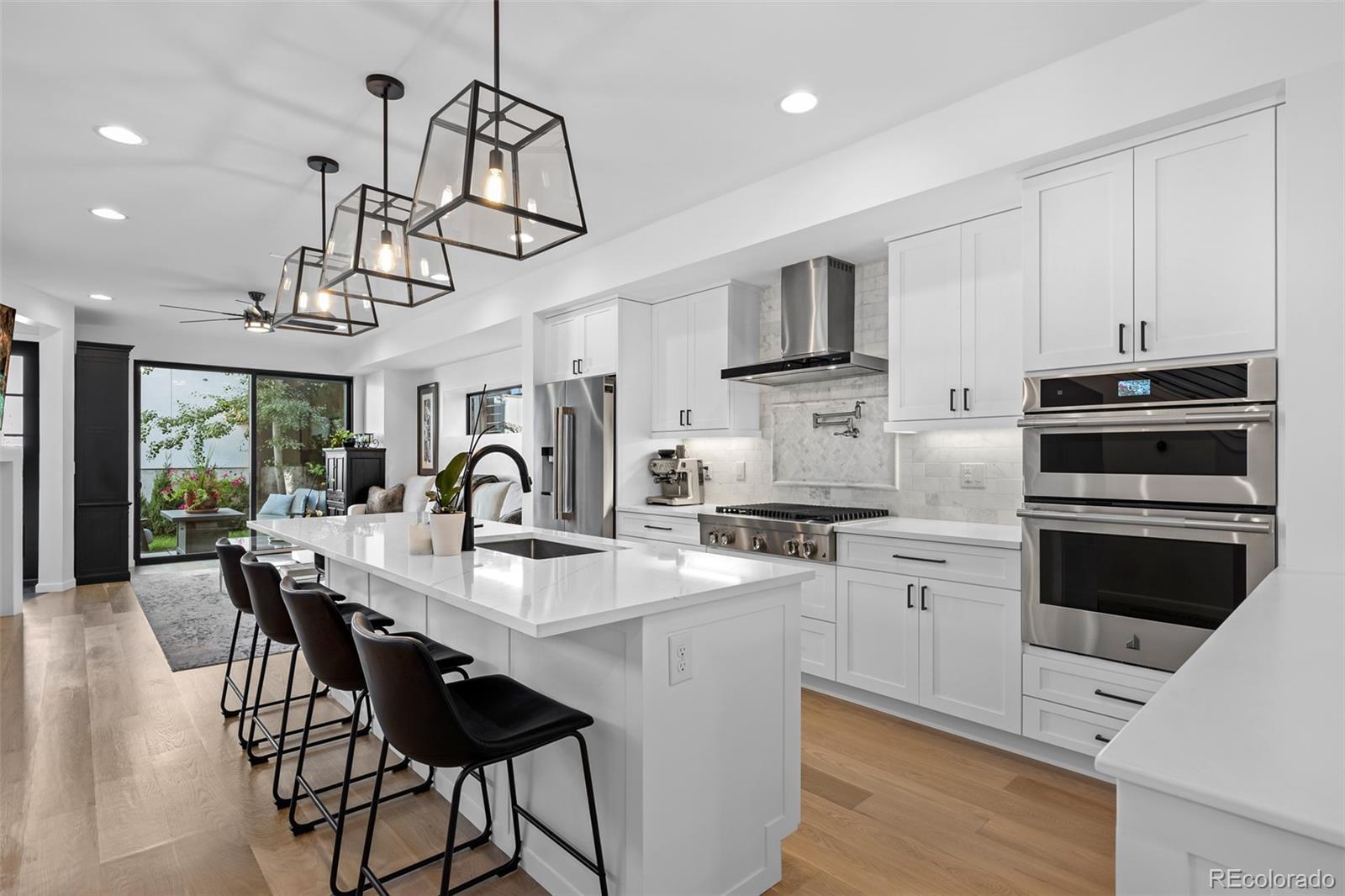 3451 Quivas Street Denver, CO 80211 - Photo 6 of 50 a kitchen with stainless steel appliances a kitchen island hardwood floor sink stove dining table and chairs